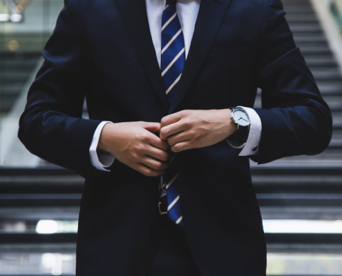 Man in a suit adjusting jacket in front of stairs